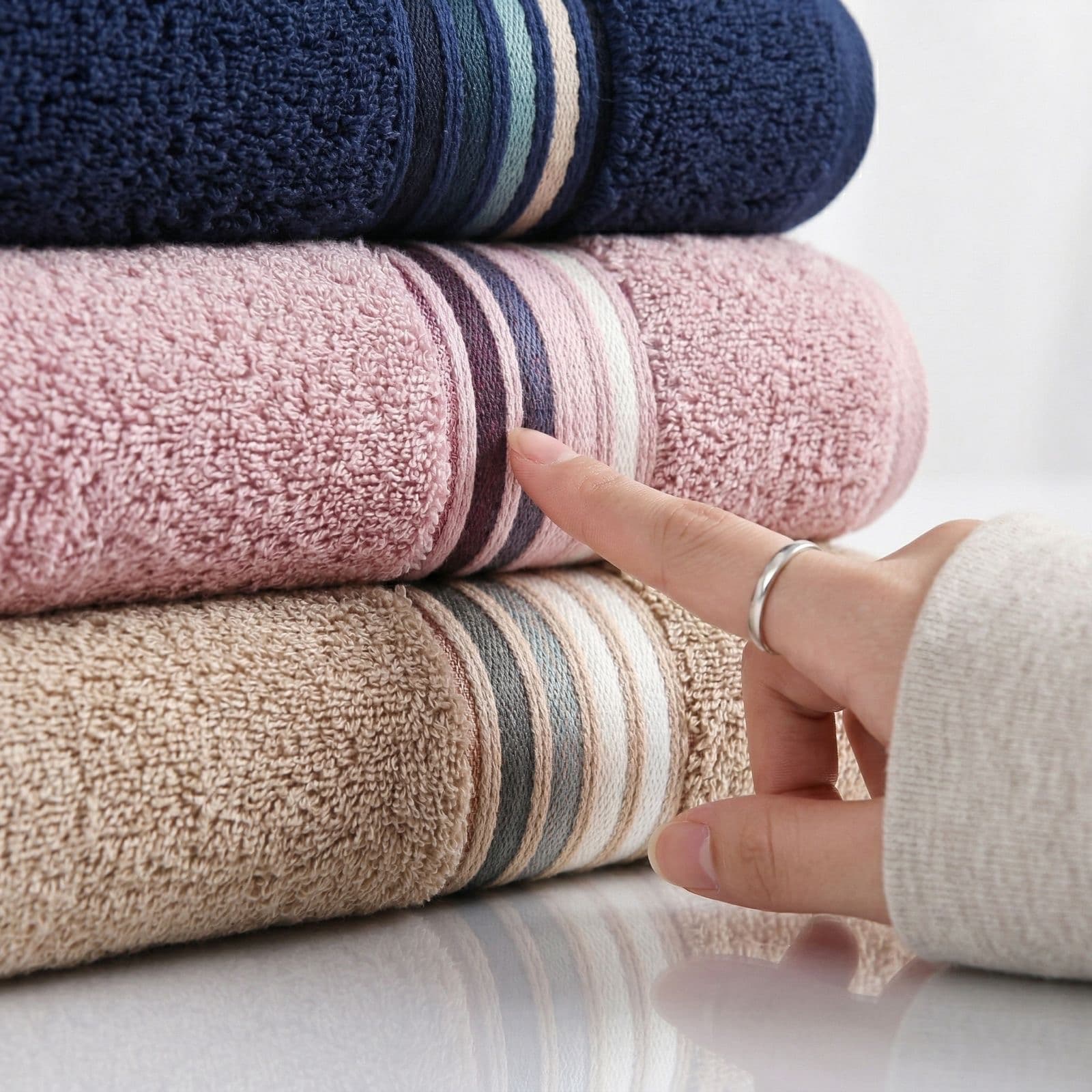 A hand touching the woven border of a rose towel